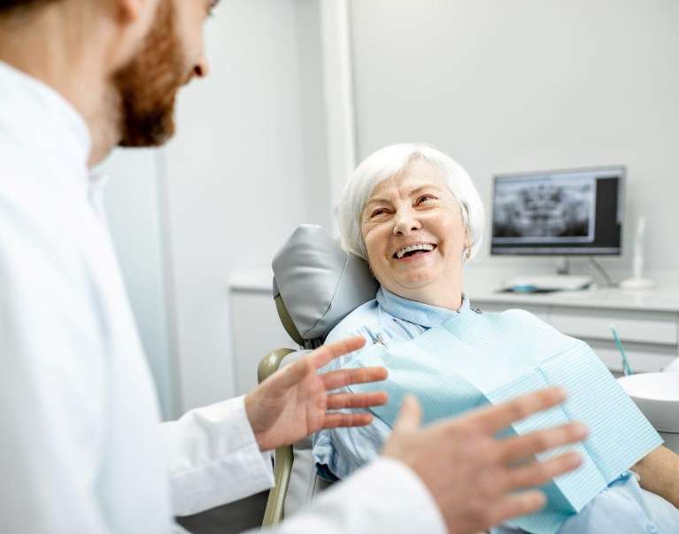 Woman in dental chair talks with dentist about senior oral health support in Chico.